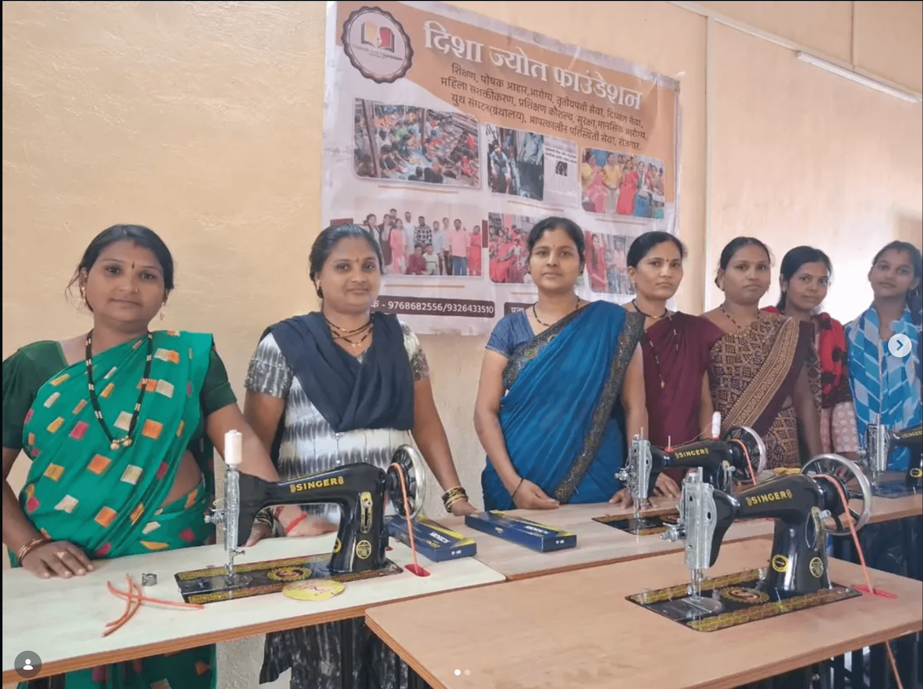 Women trainees standing with newly distributed sewing machines